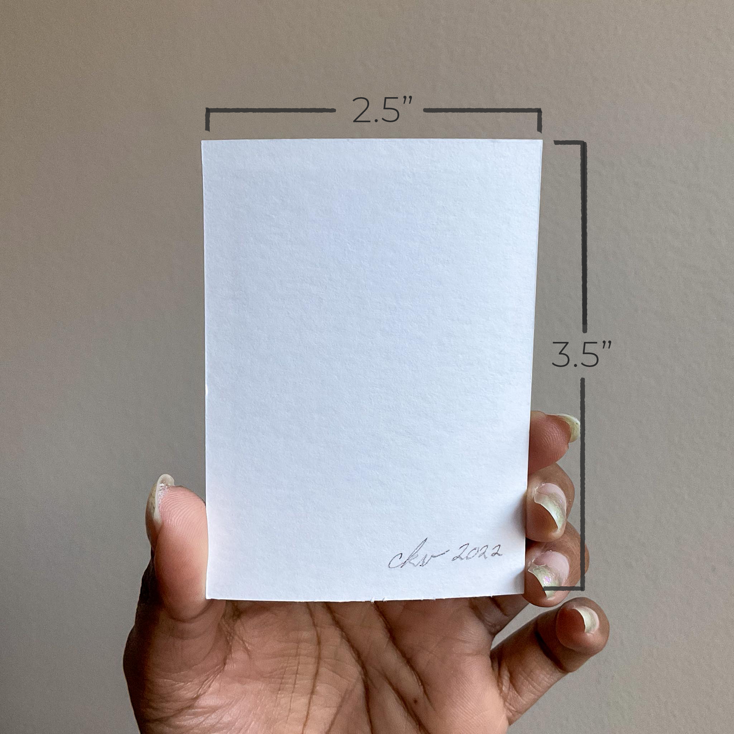 A hand holds up a piece of bristol paper against a neutral coloured wall. The paper has "ckv 2022" handwritten in the bottom right corner. It measures 2.5" by 3.5"