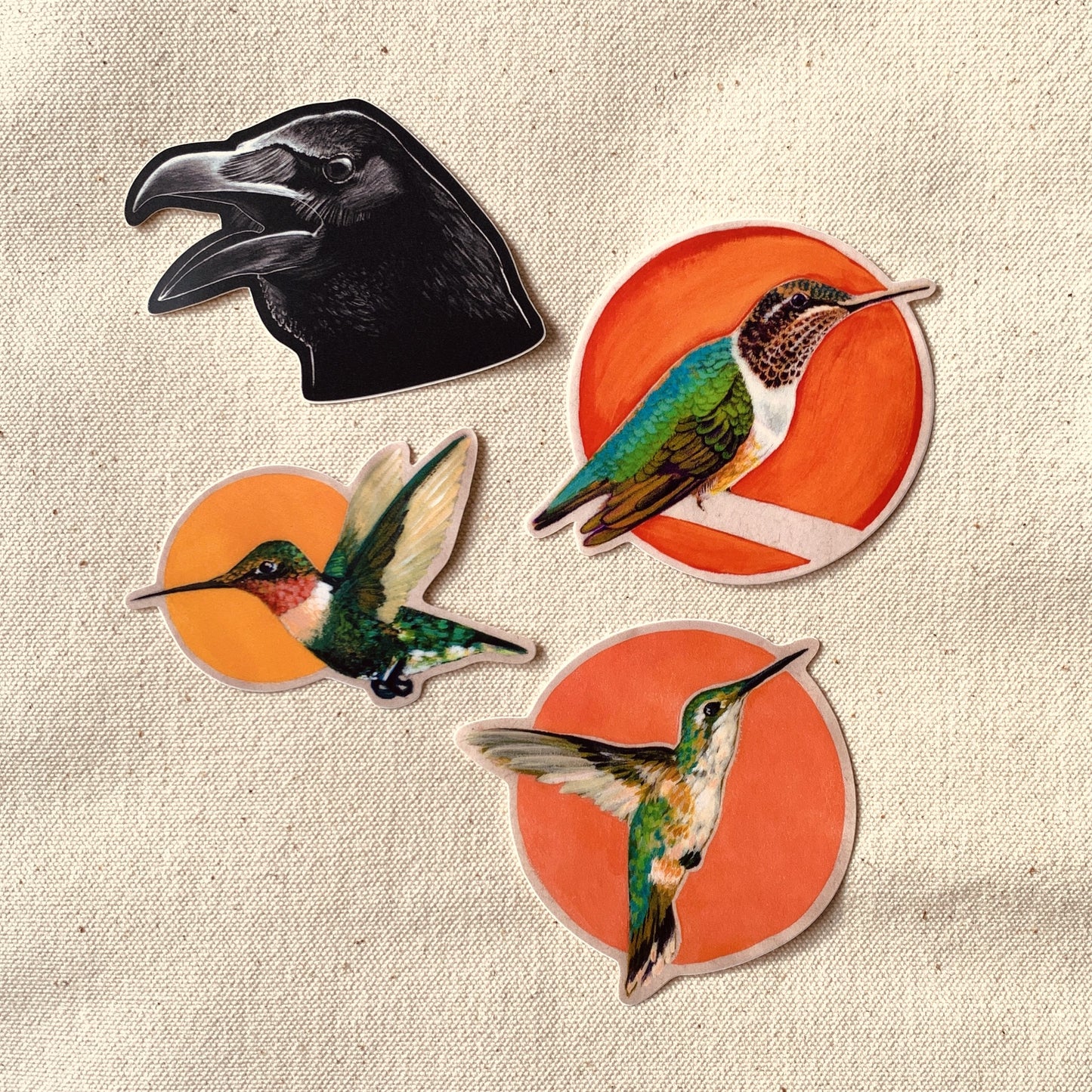 Set of raven and hummingbird stickers on a textured fabric background