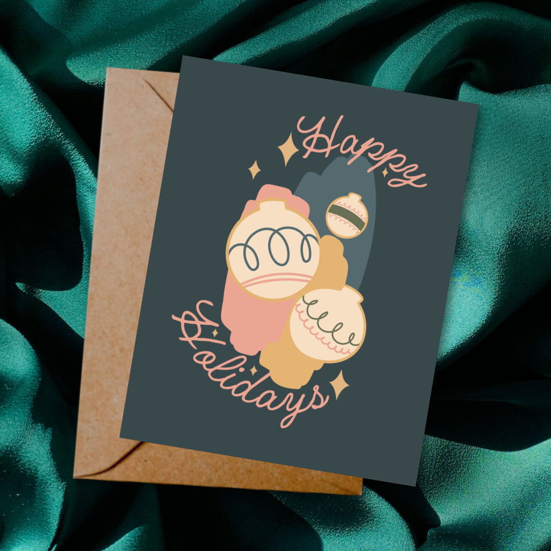 Greeting card and envelope with ornament illustration and 'Happy Holidays' text on a dark background.