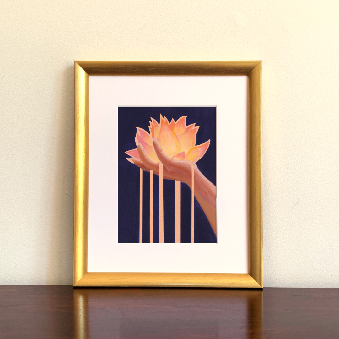Framed artwork of a hand holding a lotus flower with rose gold metallic accents against a dark background