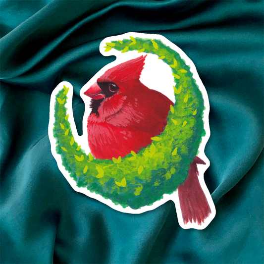 Sticker of a red cardinal bird on a green wreath against a beige background