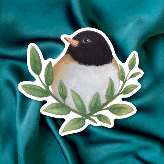 Sticker of a dark-eyed junco bird with green leaves on a beige background
